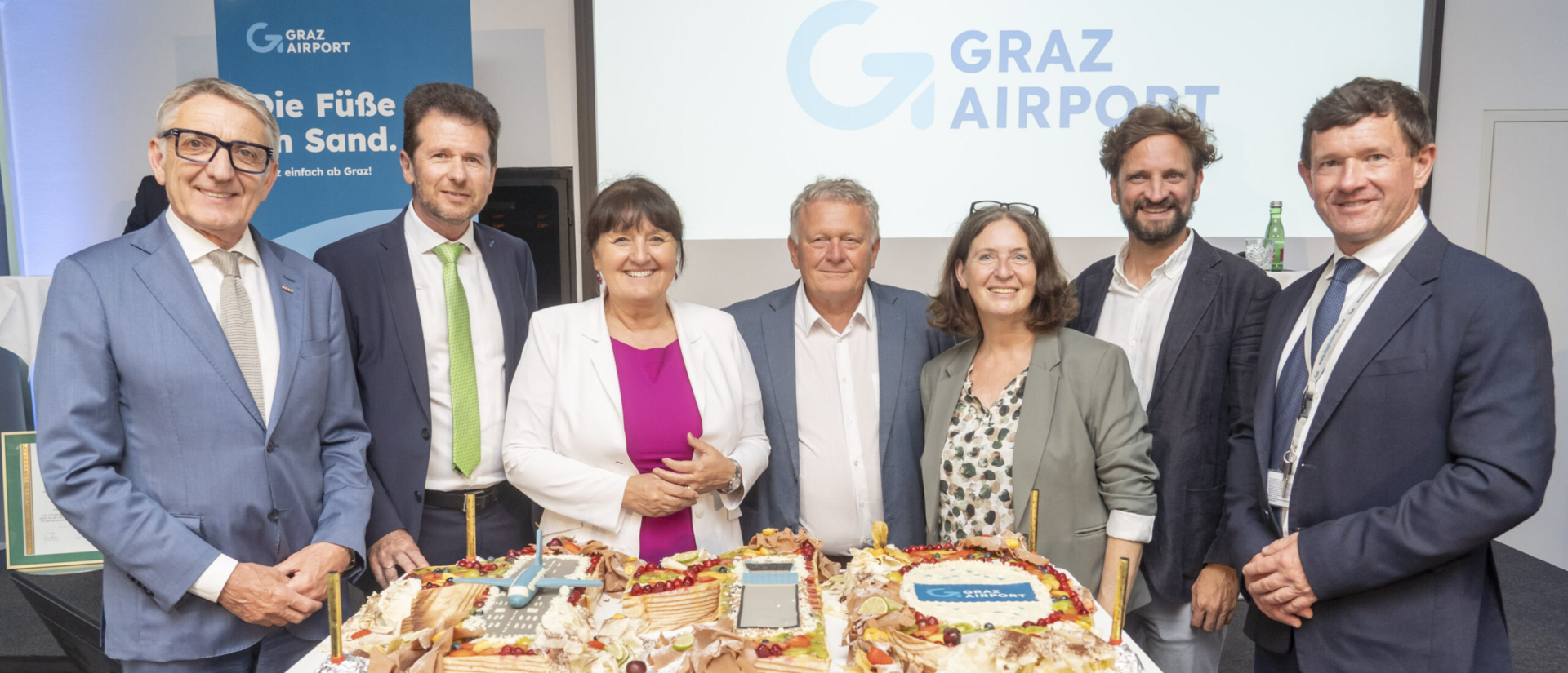 Group picture with birthday cake and new logo Jubilee celebrations for 110 years of Graz Airport (© Foto Fischer); ltr.: Josef Herk, President of the Economic Chamber of Styria, Wolfgang Grimus, Managing Director of Graz Airport, Manuela Khom, President of the Styrian Parliament, Wolfgang Malik, CEO of Holding Graz, Elke Kahr, Mayor of the City of Graz, municipal councillor David Ram, Jürgen Löschnig, Managing Director of Graz Airport