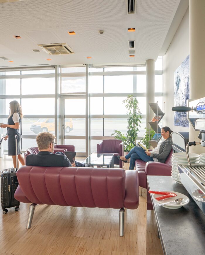 VIP-Raum mit Kaffeemaschine, bequemen Sitzgelegenheiten, Tisch und Passagieren