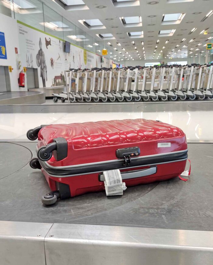 Roter Koffer auf Gepäckband