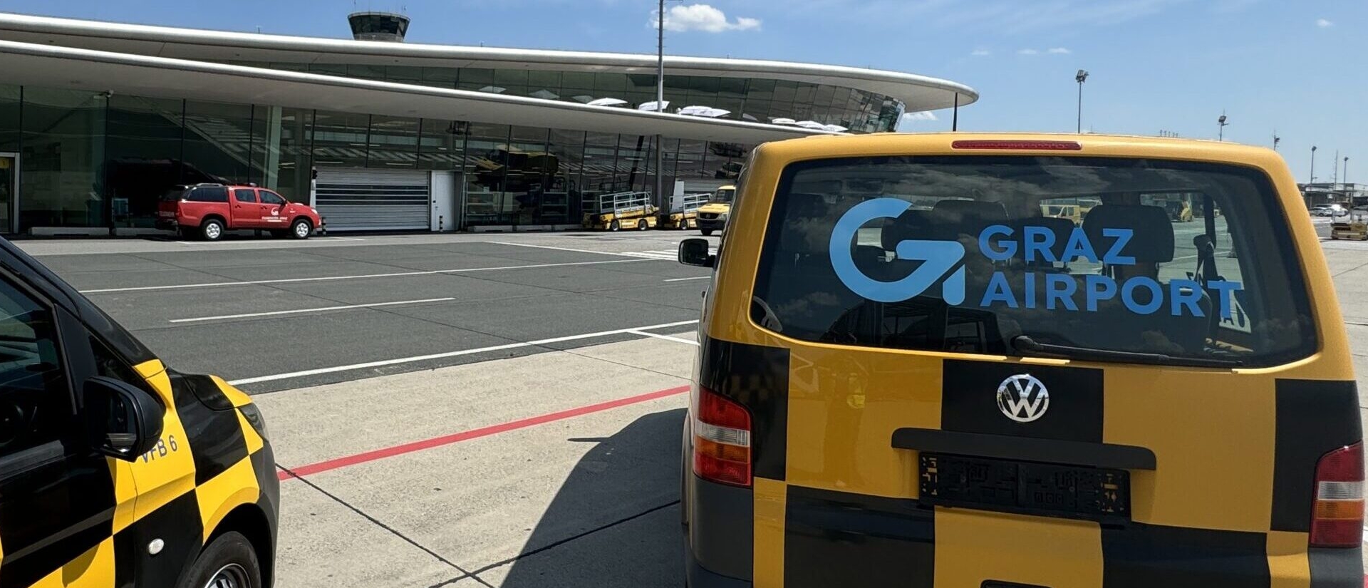 Two jellow and black vehicles in front of the terminal.