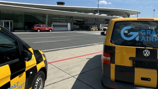 Two jellow and black vehicles in front of the terminal.