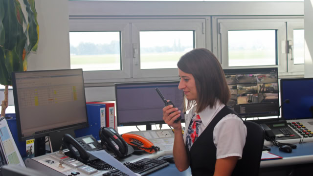 Frau mit Funkgerät vor Computern