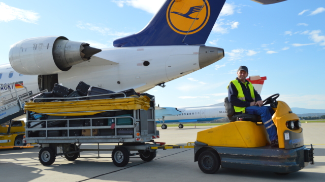 Mann mit Gepäckwagen vor Lufthansa-Maschine