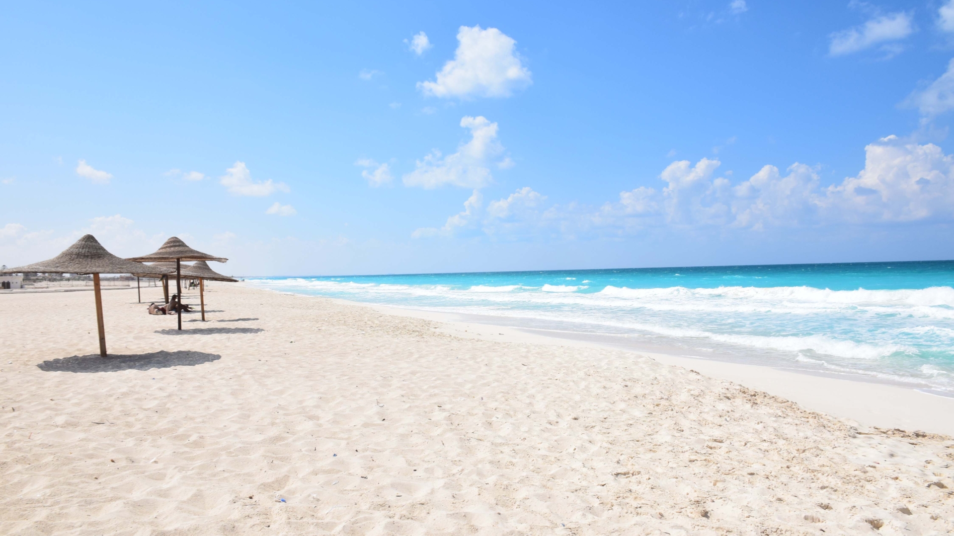 Sonnenschirme aus Stroh mit Sand und Meer.