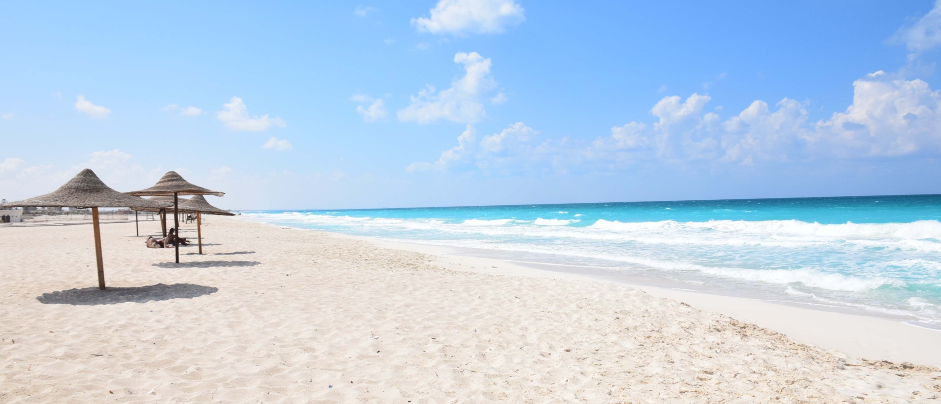 Sonnenschirme aus Stroh mit Sand und Meer.