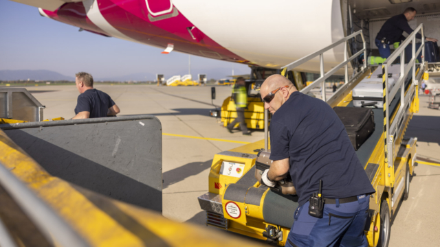 Männer laden Koffer aus Flugzeug.