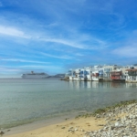 Strand mit blauem Himmel und weiß-bunten Häusern.