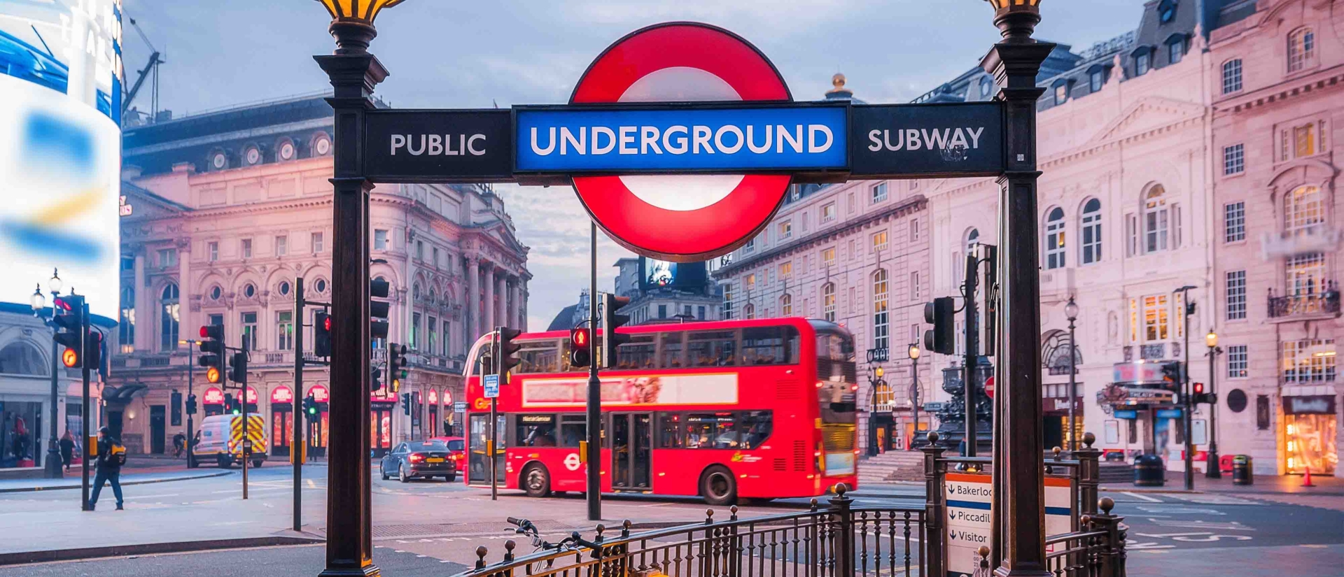 Ansicht eines Underground-Schildes vor einem beleuchteten Platz.