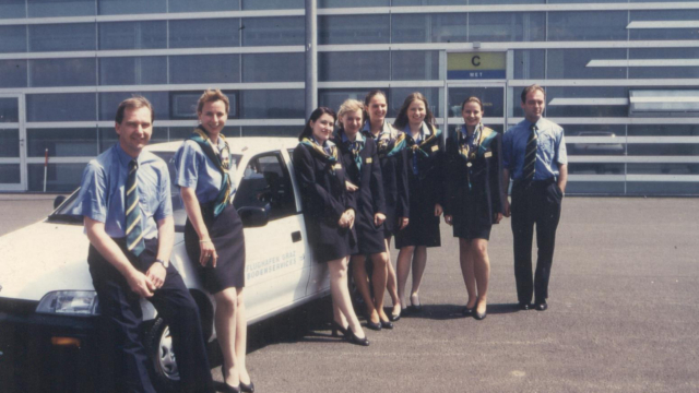 Das Team zum Start vor 30 Jahren. Foto: FGS. Personen in Uniformen lehnen an einem weißen Auto.