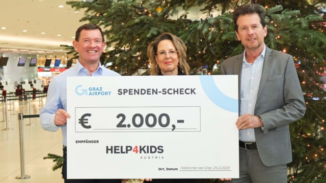 3 Personen mit Spendenscheck vor Weihnachtsbaum