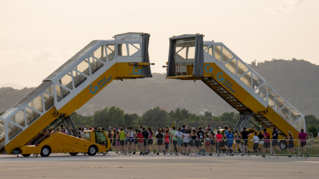 Läufer laufen unter gelben Passagiertreppen durch.