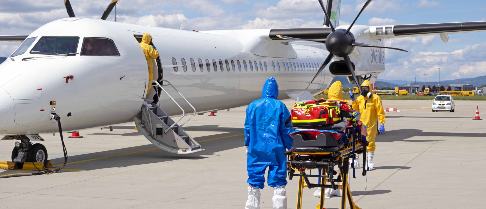 Personen mit Schutzanzügen vor einem Propellerflugzeug.